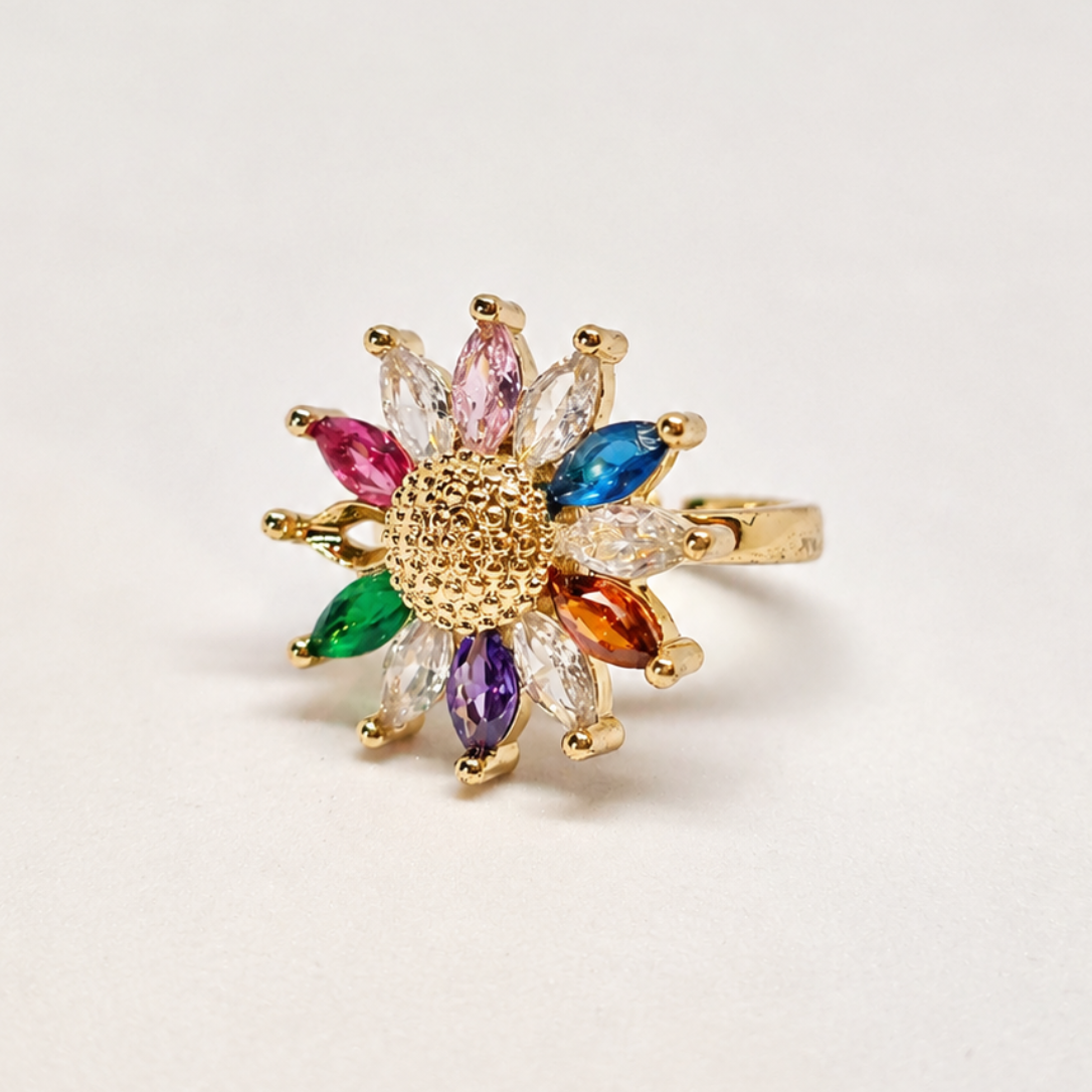 A gold flower-shaped ring with multiple colorful marquise-cut gemstones in pink, blue, green, purple, orange, and clear, set against a plain light background.